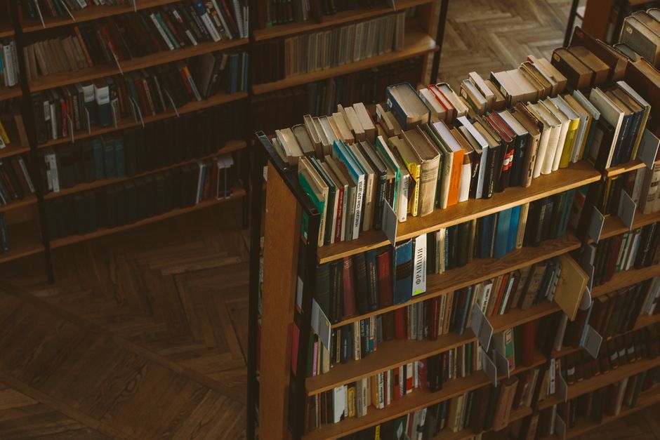 Warm-toned library scene with wooden shelves filled with books, conveying a sense of study and knowledge.